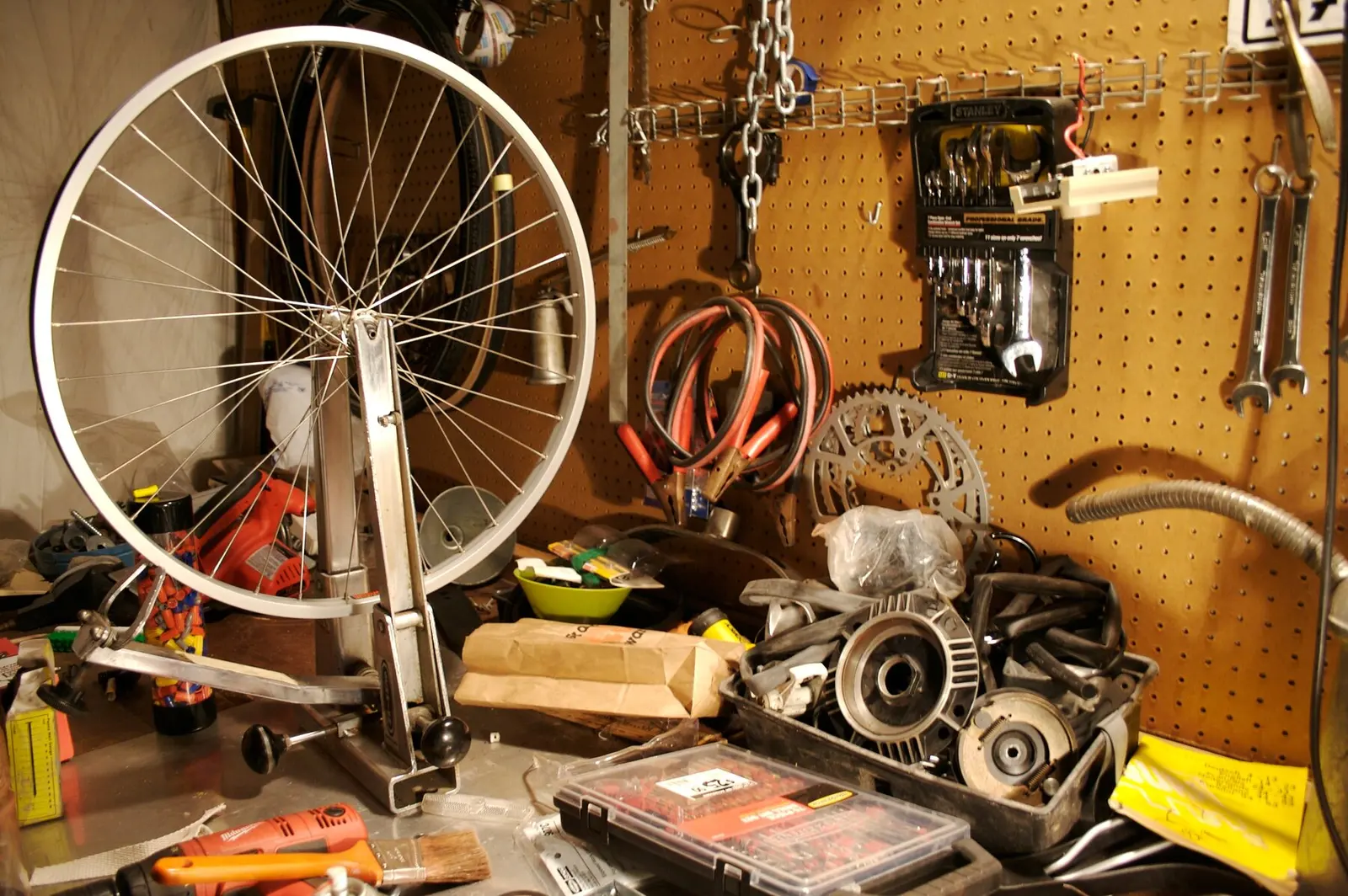 A wheel in a truing stand on a workshop bench with tools on the wall