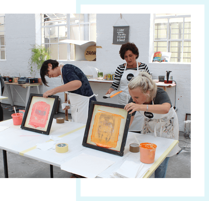 Printers pulling framed prints at a workshop table