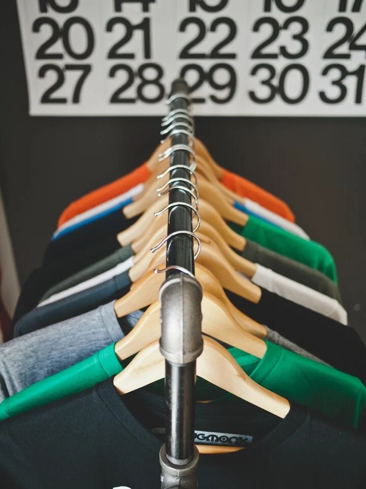 A rail of colourful T-shirts on hangers in front of a calendar